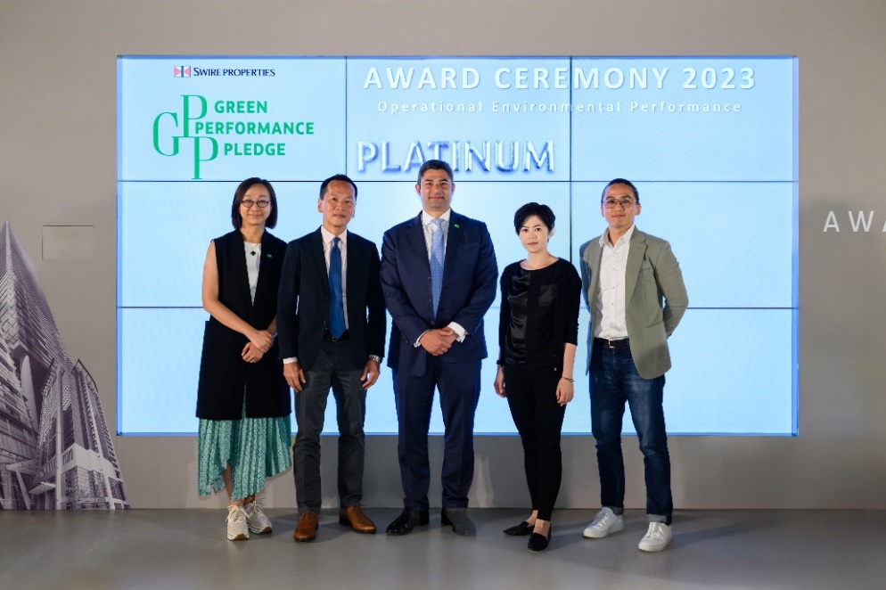 A group of people standing in front of a large screen

Description automatically generated