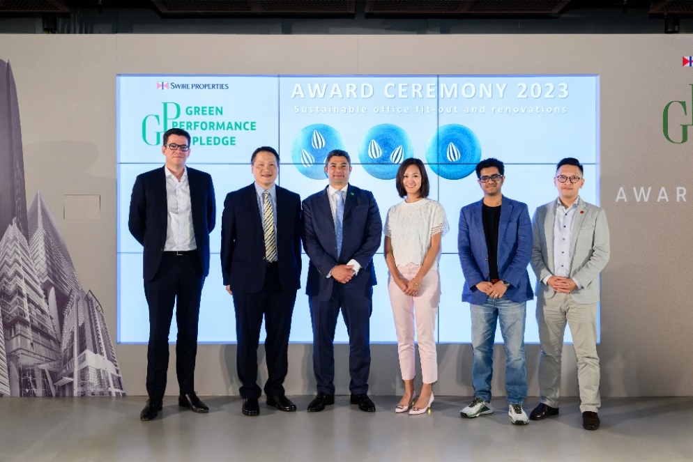 A group of people standing in front of a large screen

Description automatically generated